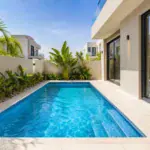 Swimming pool in a modern Dubai villa backyard with tiled decking and landscaped borders